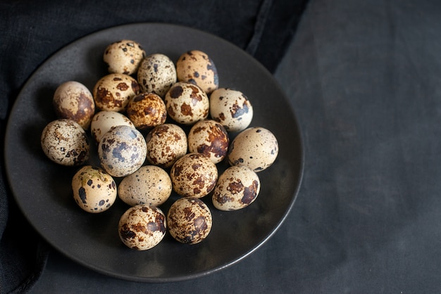 Quail eggs in plate on dark background with copy space