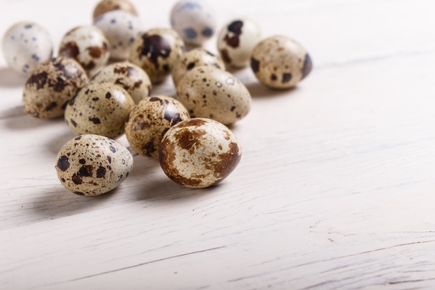 Quail eggs on a white wooden background.