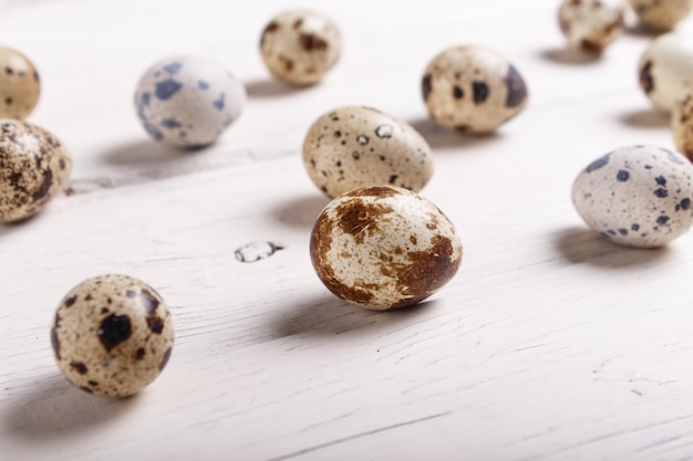 Quail eggs on a white wooden background.