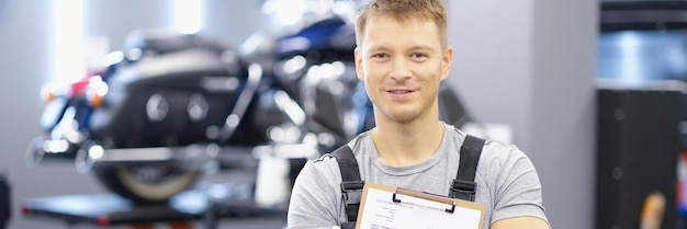 Qualified maintenance center worker in uniform posing on motorbike background