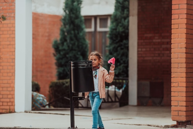 Quarantine is over concept Girl throwing away protective face mask to garbage trash can on background of blooming parkEnd of covid19 pandemicfreedomvictorywin Selective focus High quality photo