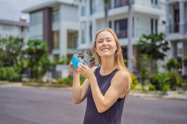 Quarantine is over concept woman taking off mask against the background of small town houses we are