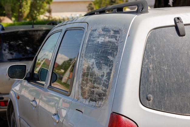 Photo quarter window of silver suv broken and covered with several layers of transparent adhesive tape