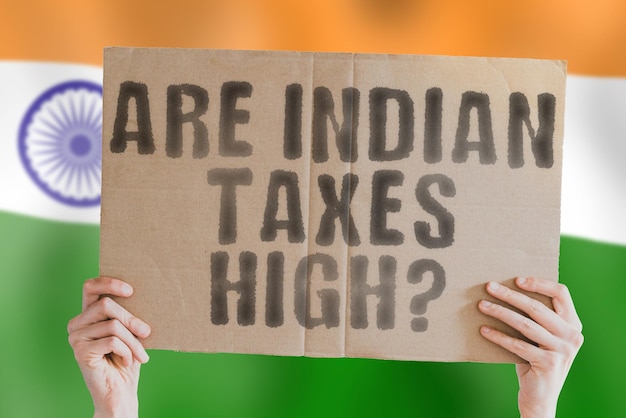 The question Are Indian taxes high on a banner in men's hand with blurred Indian flag on the background Increase Court Deal Choice Bank Counts Success Stress Stock Service Sell