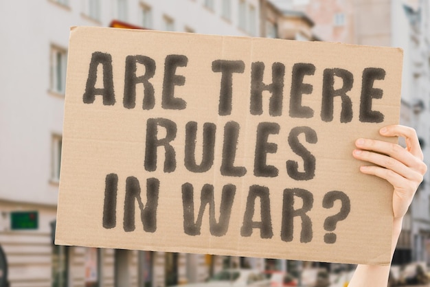 The question Are there rules in war is on a banner in men's hands with blurred background Evil Failure Injury Break Offense Criminality Dishonesty Violation Sin Illegality Fighting