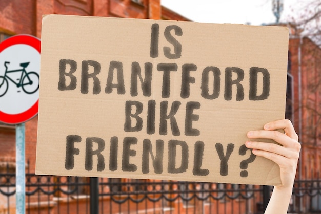 The question Is Brantford bike friendly on a banner in men's hand with blurred background Transportation Zero waste Bicycle lane Streets City Safety Insecure Road signs Dangerous