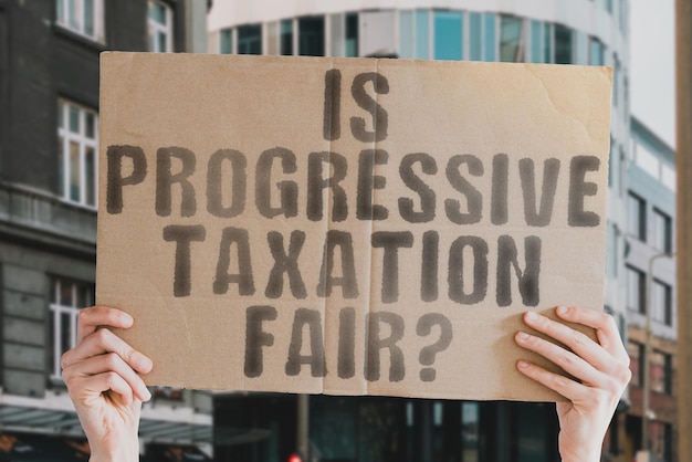 The question Is progressive taxation fair is on a banner in men's hands with blurred background Federal Increase Growing Grow Potential Up System Trend Return Revenue Sale Office