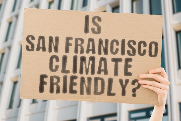 The question Is San Francisco climatefriendly is on a banner in men's hands with blurred background Support Team Activist Urban Sunset Carbon Ecology Energy New Clean Warming Waste