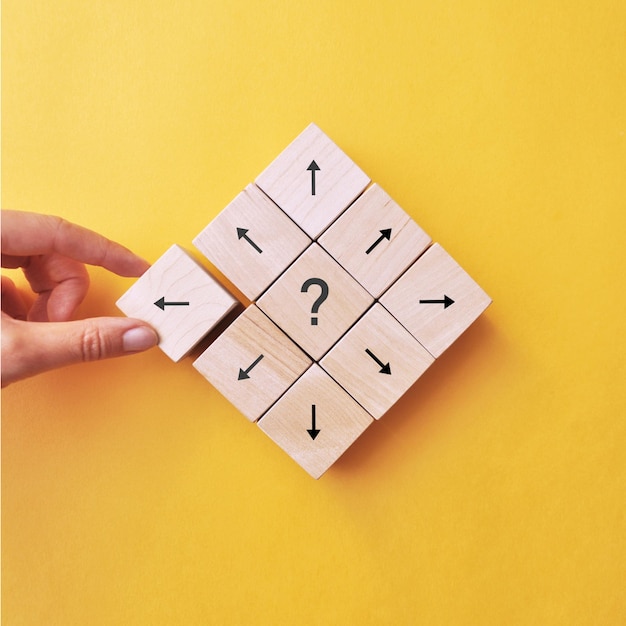 Question mark and arrows on wooden cubes, a person chooses one solution from many others