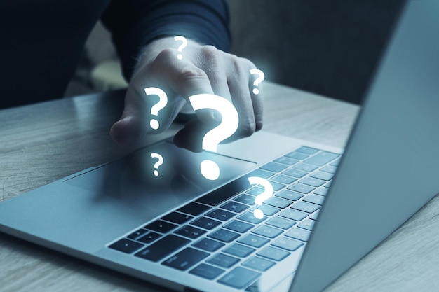 Question mark concept or FAQ Person touches on a hologram next to a laptop