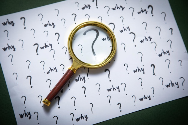 Question marks and Why word with magnifying glass