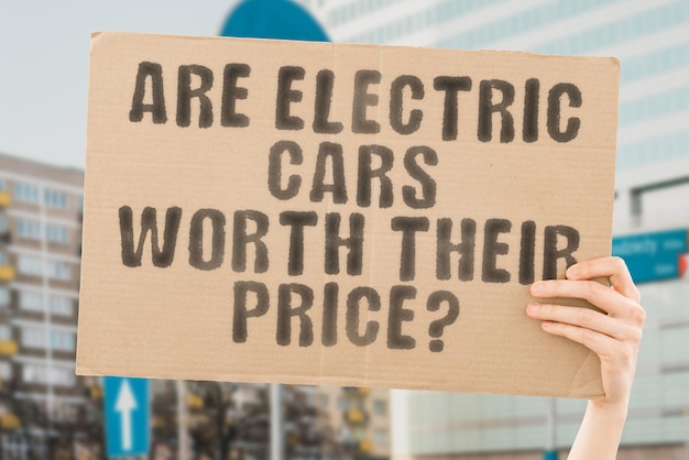 The question What is the future of electric cars is on a banner in men's hands with blurred background Clean Recharge Industry Modern Plug Charge Ecological Renewable Drive