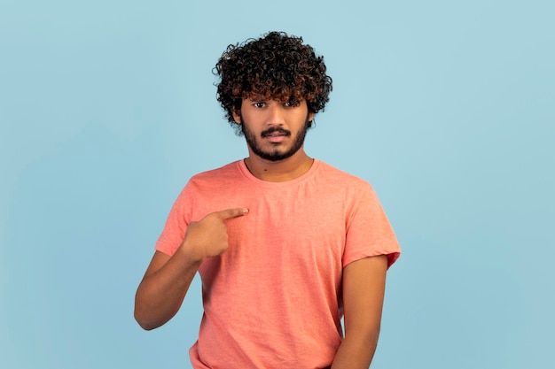 Questioned handsome indian man looking surprised pointing himself