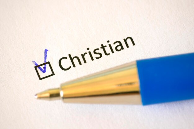 Questionnaire blue pen and the inscription CHRISTIAN with check mark on the white paper