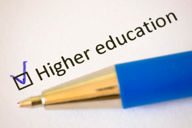 Questionnaire Blue pen and the inscription HIGHER EDUCATION with check mark on the white paper