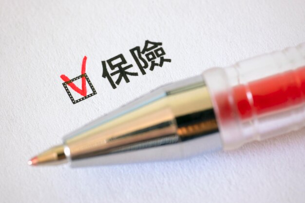 Questionnaire red pen and the inscription INSURANCE with check mark on the white paper