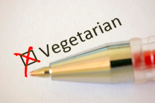 Questionnaire Red pen and the inscription VEGETARIAN with cross on the white paper