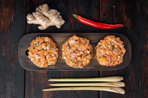 Quick asian raw fish patties with herbs, on old wooden table, flat lay