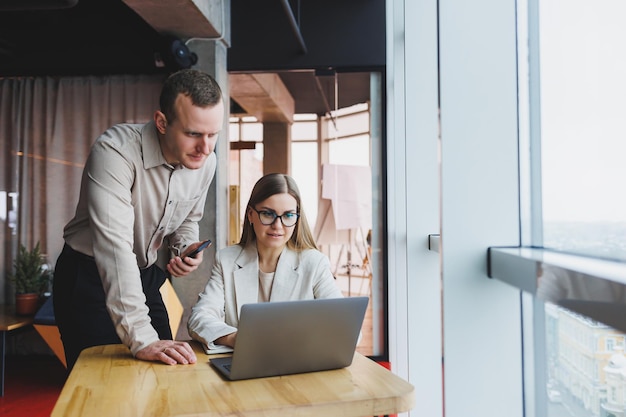 Quick business conversation of business partners A group of young confident business people are discussing something while spending time in a modern office they are looking into a laptop