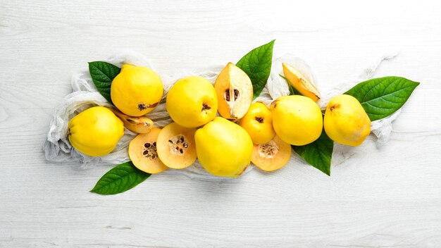 Quince fruits with leaves on white wooden background