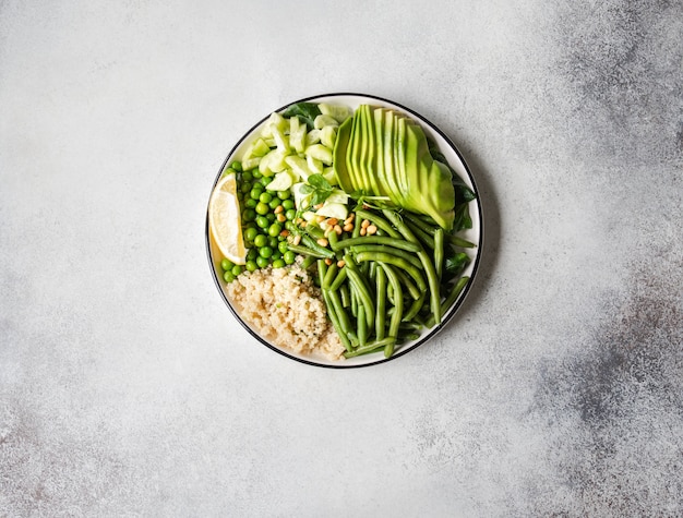 Quinoa bowl with green beans, green peas, cucumber, avocado, and pine nuts on a grey