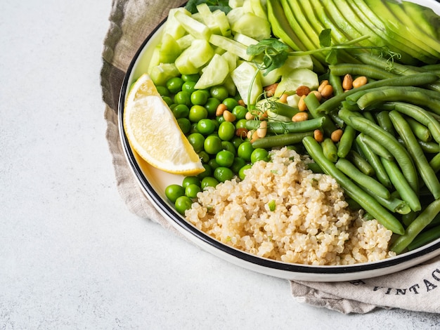 Quinoa bowl with green beans, green peas, cucumber, avocado, and pine nuts