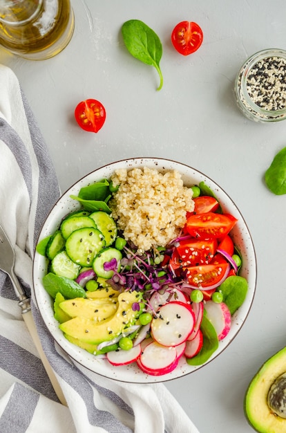 Quinoa salad with fresh vegetables, spinach, green peas, microgreens, and sesame seeds