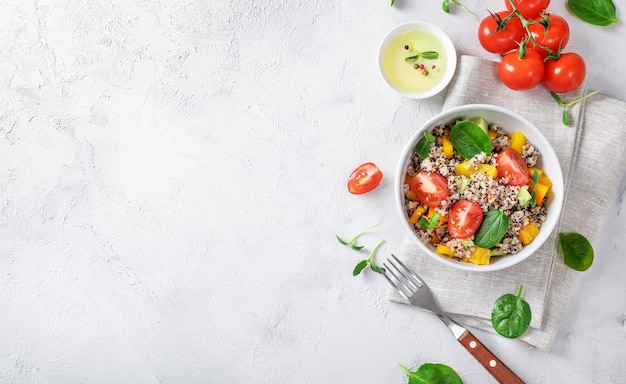 Quinoa salad with tomatoes, batata and spinach on white backround. Vegan food concept. Top view. Copy space.