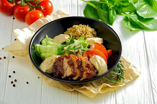 Quinoa with chicken and salad on a black plate Bowl superfood