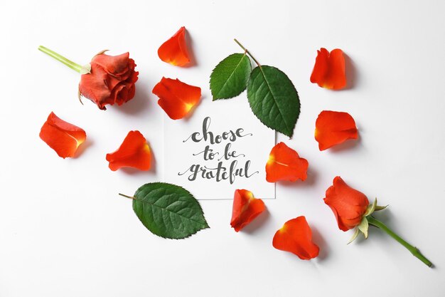 Quote Choose to be grateful written on paper with petals and leaves on white background Top view