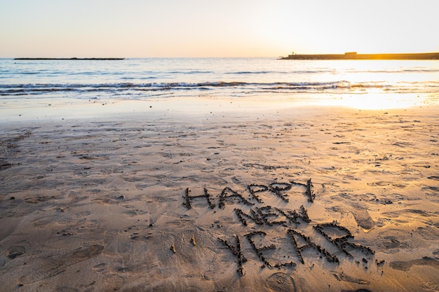 QuotHappy new yearquot written on the beach during sunset photo with copy space