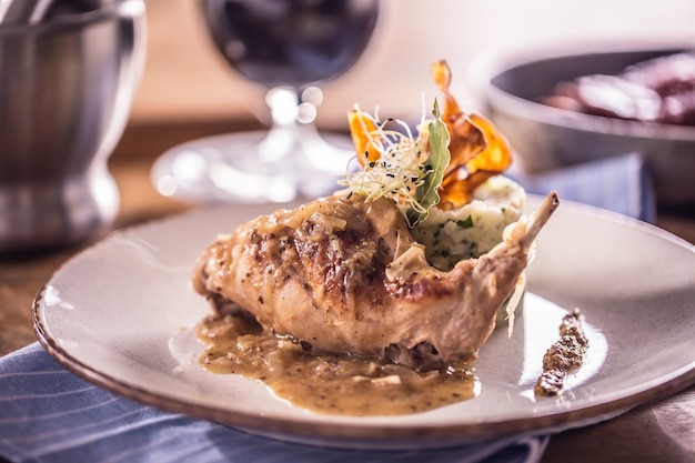 Rabbit leg with mashes potatoes and decoration on plate in restaurant.