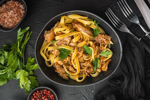 Rabbit stew tagliatelle set, in bowl, on black stone table, top view flat lay