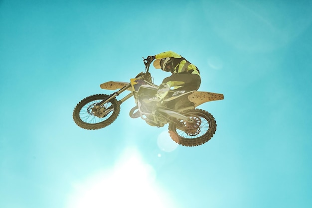 Racer on motorcycle dirtbike motocross crosscountry in flight jumps and takes off on springboard against sky Concept active extreme rest