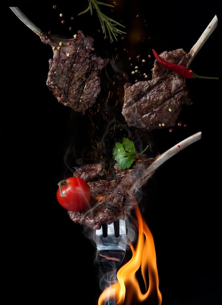 rack of lamb on fork over burning flame on black background Food levitation concept