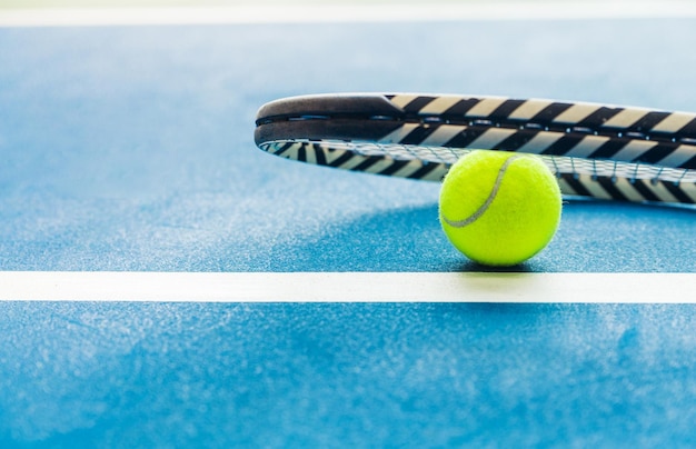 Racket and padel ball on blue court Horizontal photo