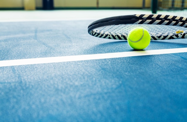 Racket and padel ball on blue court Horizontal photo