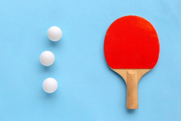 Racket for table tennis with balls on blue background.