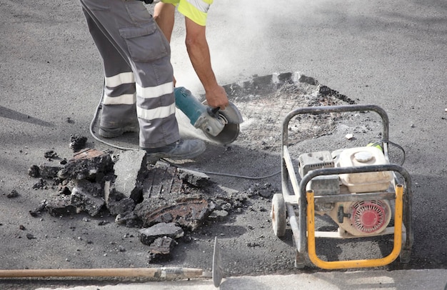 radial in the hands of asphalt worker cuts the soil and portable electric generator