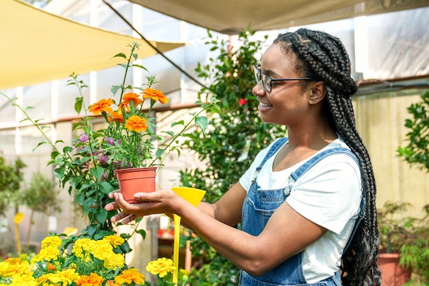 Radiant AfroAmerican Gardener Delighted with Striking Orange Flower in Lush Colorful Plant Nursery