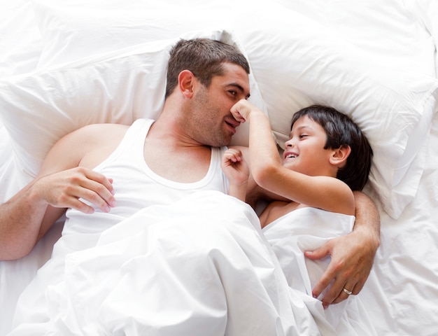 Radiant mother and her daughter looking at the camera on the bed