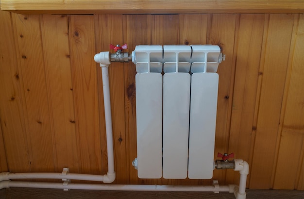 The radiator of a home heater on the background of a wooden wall in a typical Russian apartment or private house