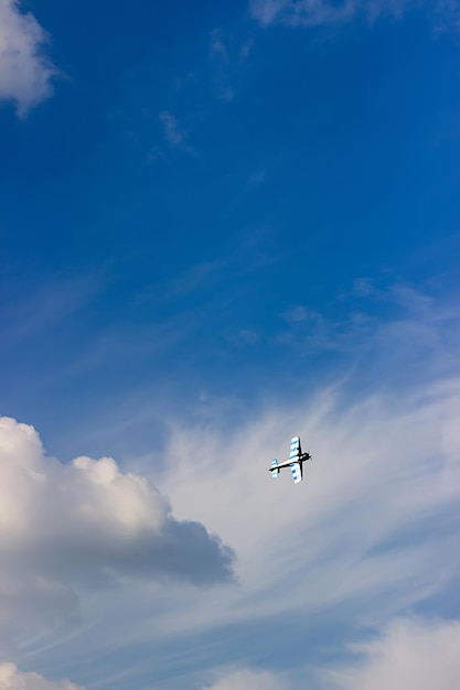 Radio controlled toy airplane against blue sky with white clouds. RC model airplane flying in the blue sky. Airplane hobby.