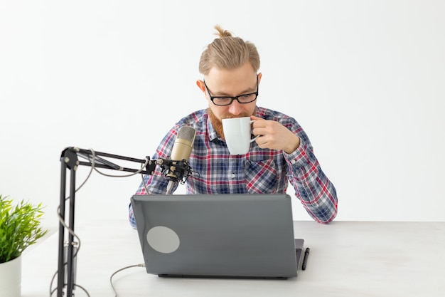 Radio host, streamer and blogger concept - Handsome man working as radio host at radio station sitting in front of microphone