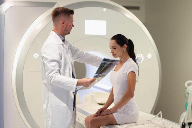 Radiologist looks at mri results and puts his hand on shoulder of sad patient computed