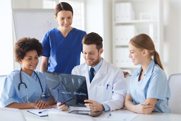 radiology, people and medicine concept - group of happy doctors looking to and discussing x-ray image at hospital