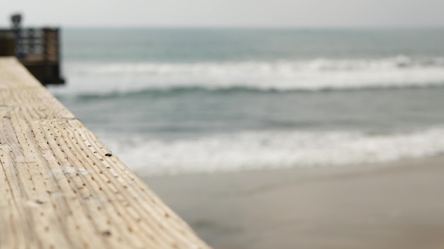 Photo railings of wooden pier, waterfront boardwalk, beach, california coast usa. ocean waves.