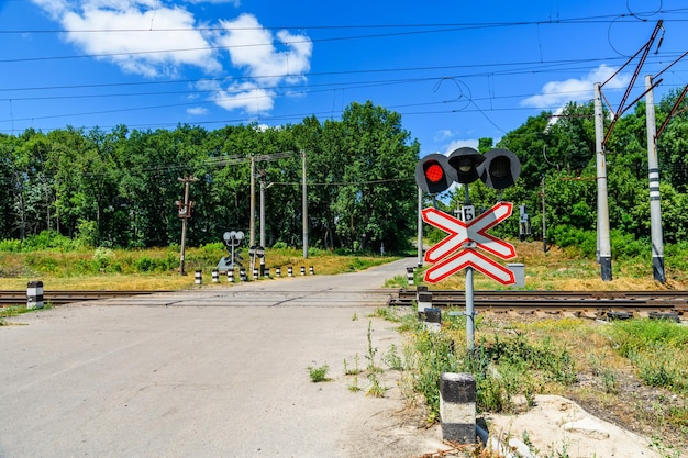 Railroad crossing sign and blinking semaphore in front of the railroad crossing