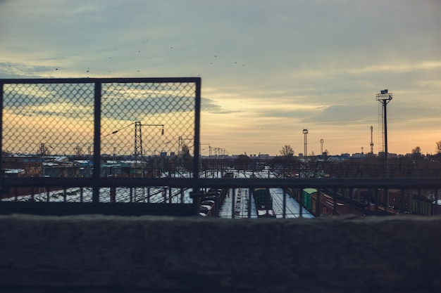 Railway station with freight trains and containers at sunset. Urban industrial background.