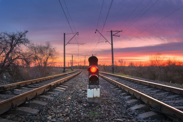 Railway station with semaphore against beautiful sky at sunset